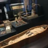 Вид на Зал II в Григорианский Египетский музей с открытым деревянным гробом Аменирдис и другими саркофагами