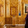 Посетительница музея внимательно рассматривает детали, которыми украшена Янтарная комната